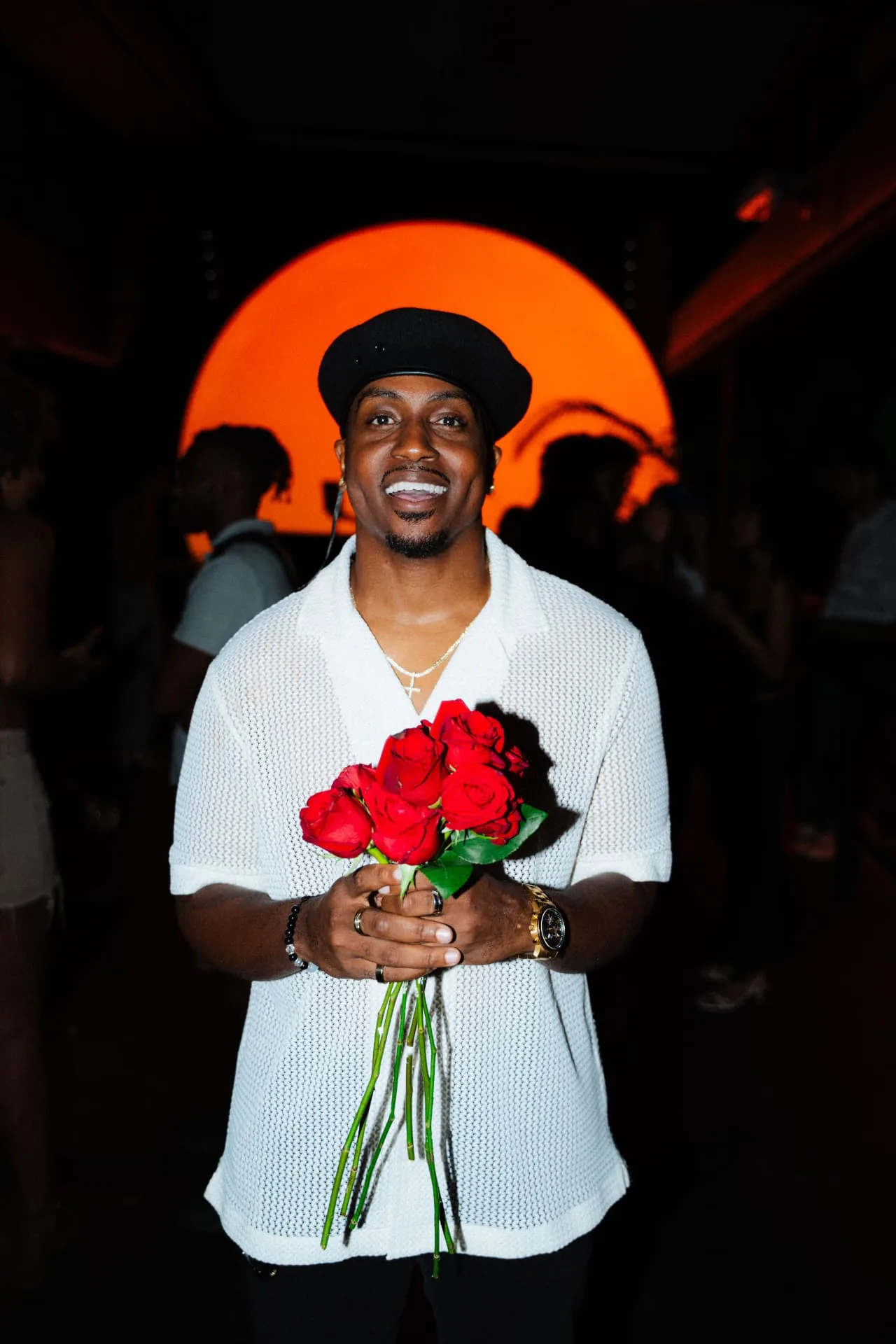 Marcus holding red roses at a night event
