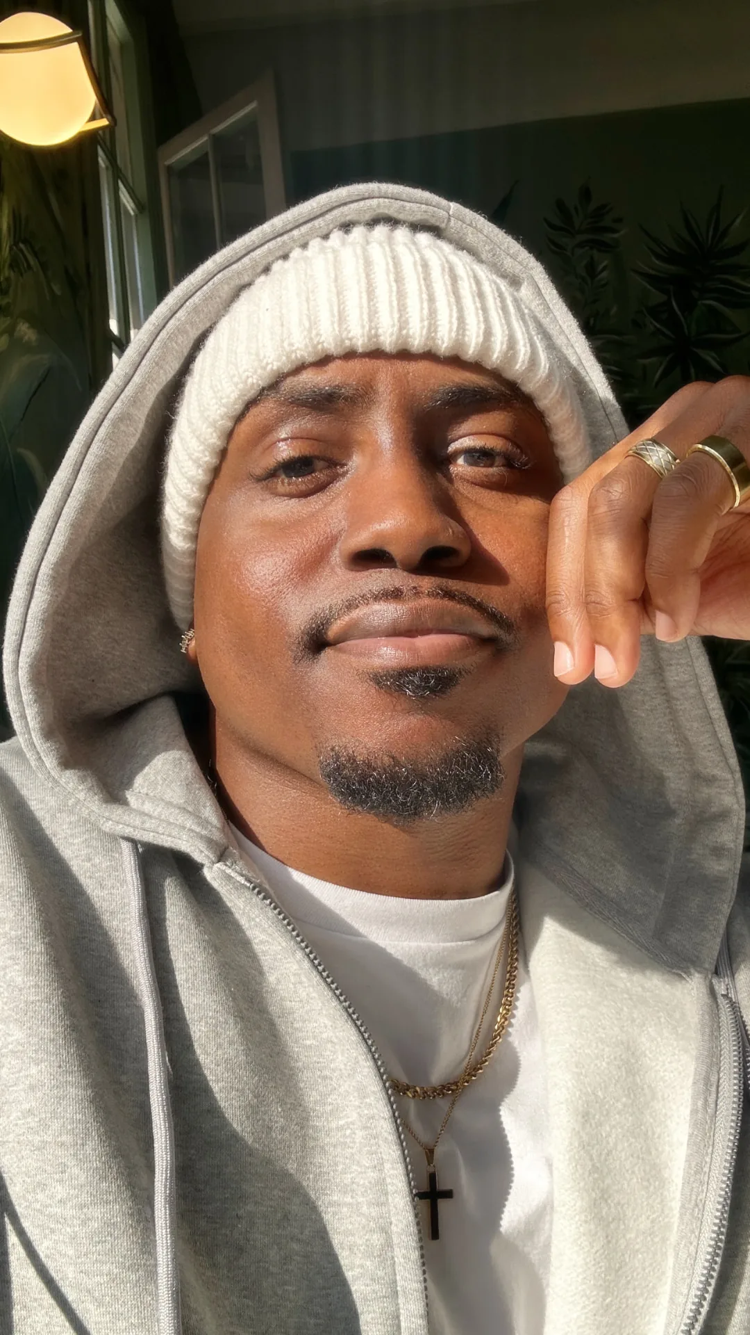Close-up of Marcus in a cream beanie and grey hoodie in golden-hour light
