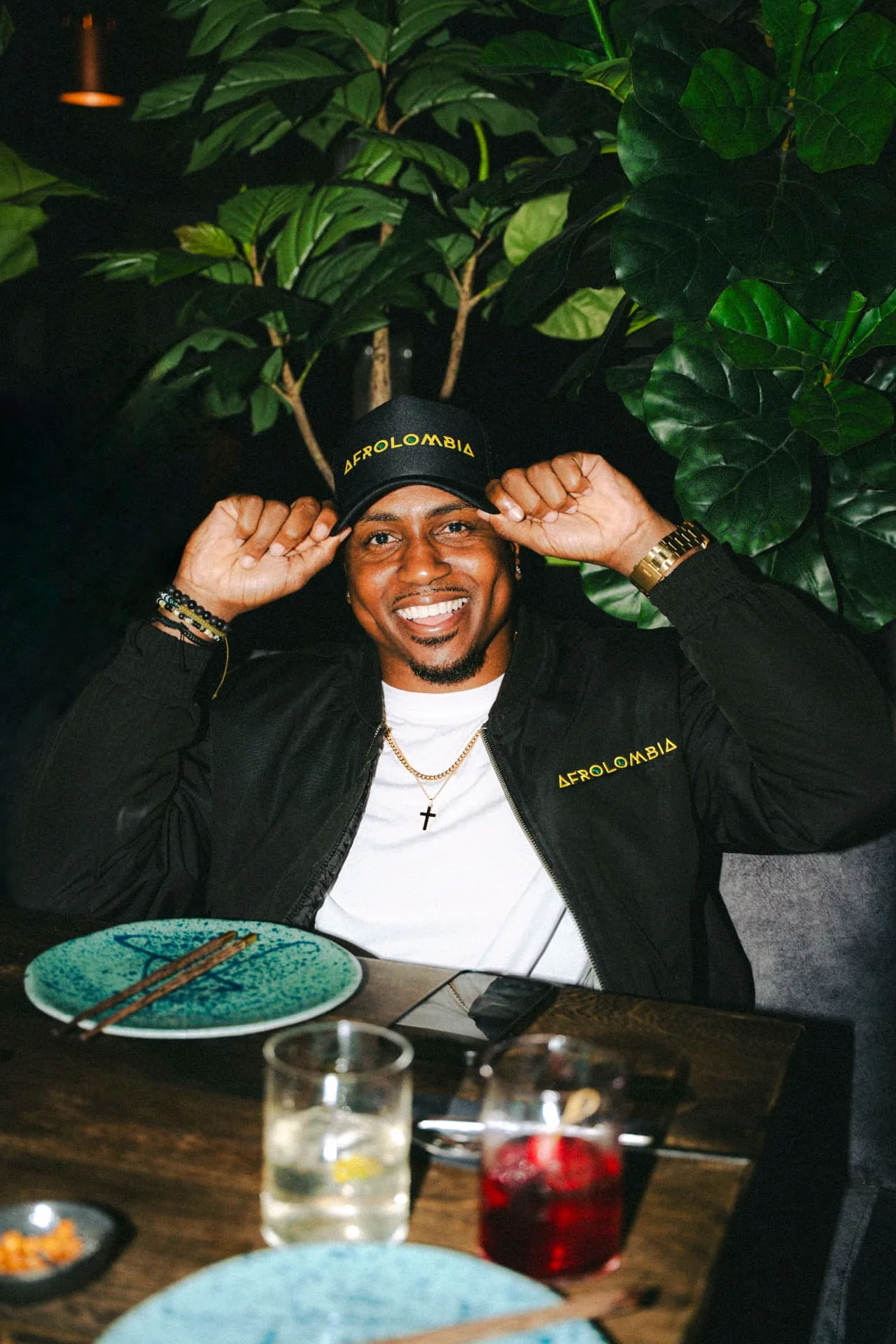 Marcus in an AFROLOMBIA cap and jacket at dinner