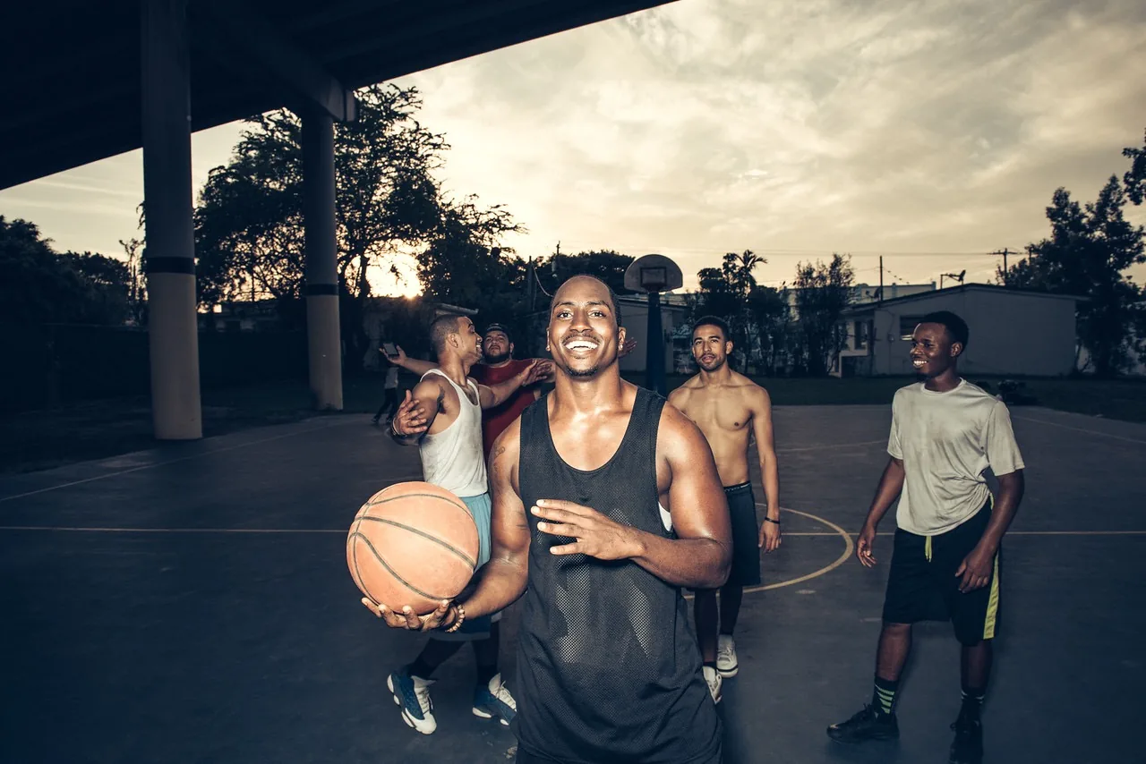 Marcus holding a basketball on an outdoor court with his crew under an overpass