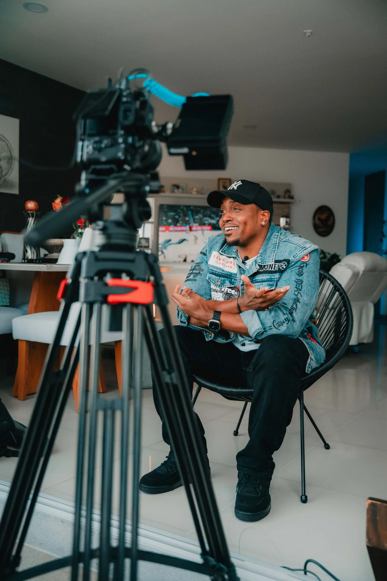 Marcus being interviewed on camera in a denim jacket and Yankees cap