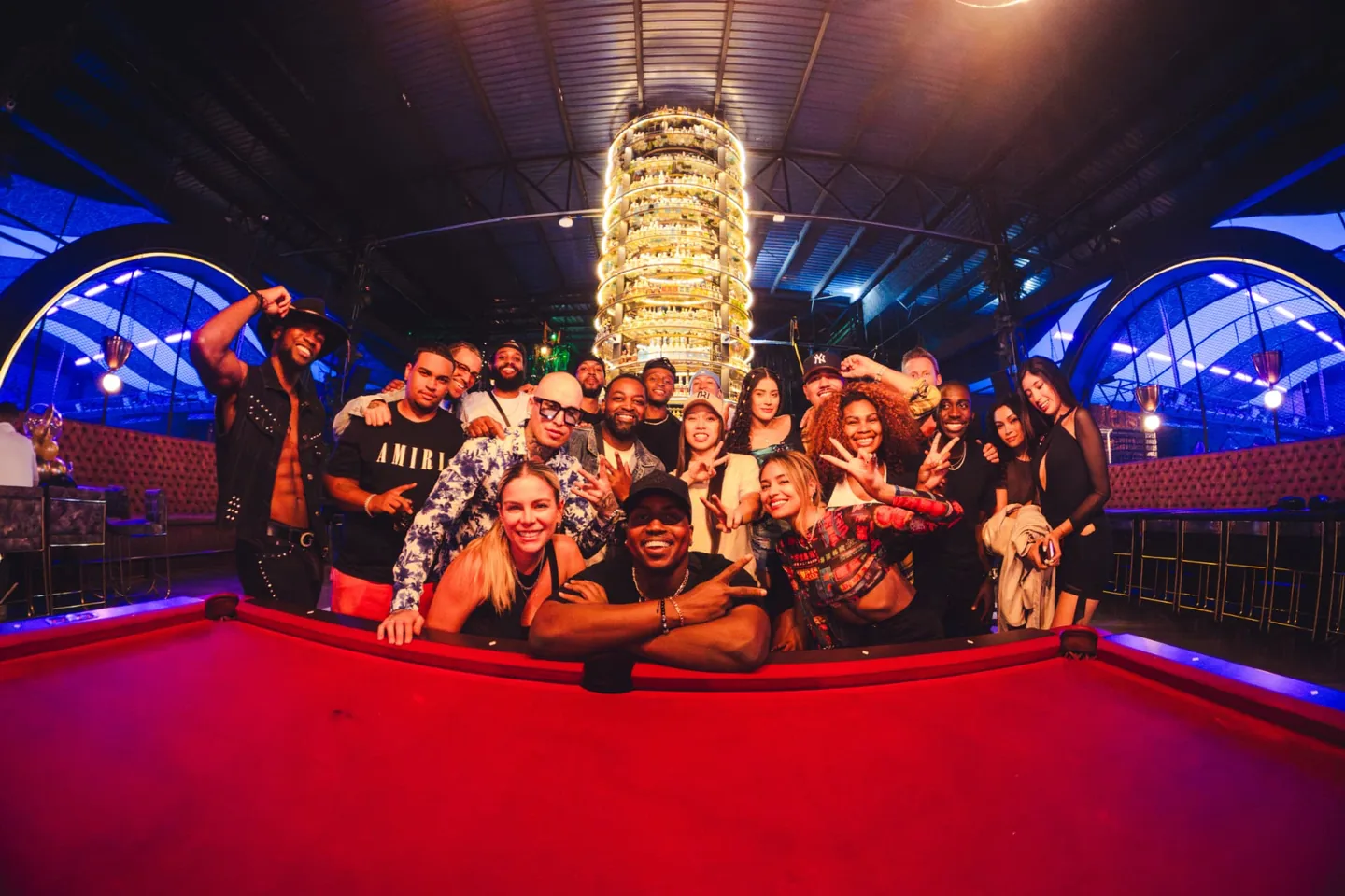 Marcus and a big crew gathered around a red pool table at a night event