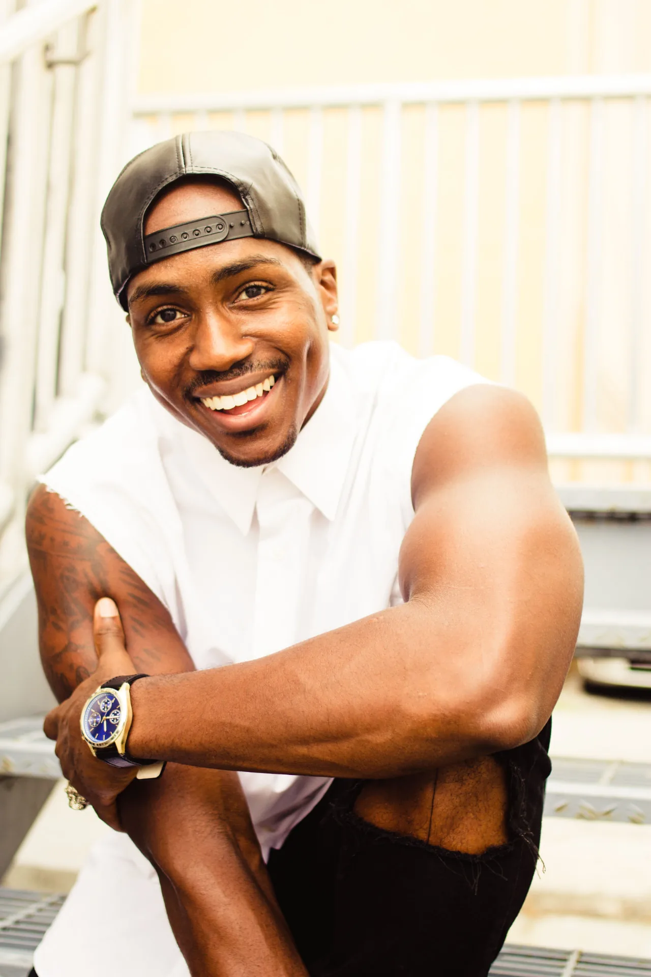 Marcus in a backwards cap and white shirt sitting on outdoor steps